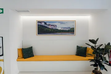 Banco de espera con cojines y cuadro de paisaje · Clínica Dental Divina Pastora, Ansoáin